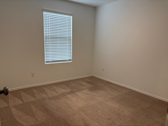 147 Gabbro Gardens Maxwell, TX 78656 - Photo 11 of 14 Neutral-toned carpeting with a distinct geometric pattern spans the room, complemented by light-colored walls