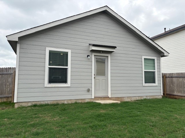 147 Gabbro Gardens Maxwell, TX 78656 - Photo 13 of 14 Rear exterior featuring light gray horizontal siding, a gabled roofline, and a fenced perimeter