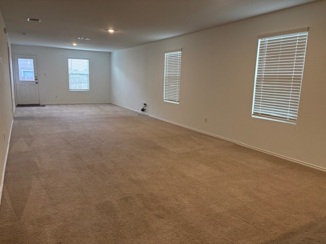 147 Gabbro Gardens Maxwell, TX 78656 - Photo 4 of 14 Spacious room featuring neutral carpet flooring, recessed lighting, baseboards, and multiple windows with blinds