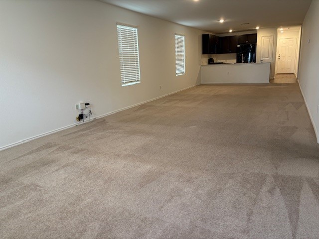 147 Gabbro Gardens Maxwell, TX 78656 - Photo 5 of 14 Spacious open-concept room featuring neutral-toned carpeting, white walls, and two windows with blinds
