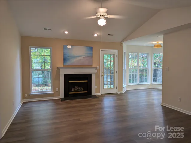an empty room with wooden floor fireplace and windows