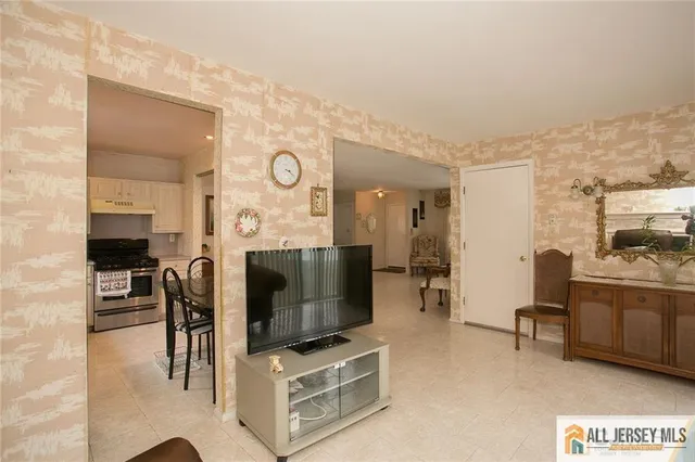 a living room with furniture a flat screen tv and kitchen view