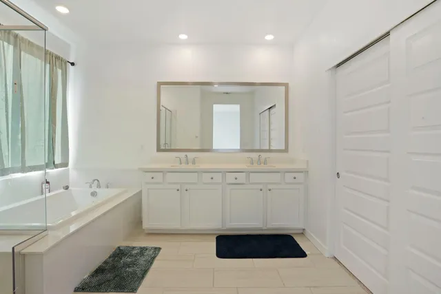 a bathroom with a sink a large mirror and a bathtub