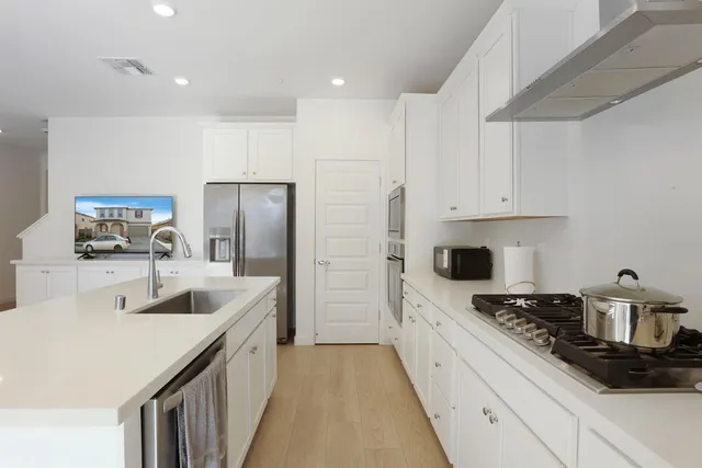 a kitchen with stainless steel appliances a sink a stove a refrigerator and cabinets