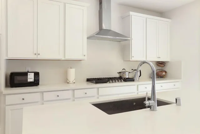 a kitchen with granite countertop white cabinets and a sink