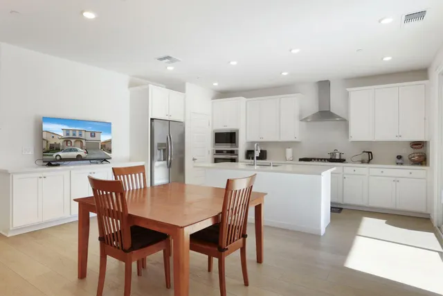 a kitchen with a dining table chairs and refrigerator