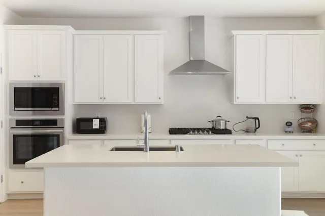 a kitchen with stainless steel appliances granite countertop a sink a stove and a white cabinets