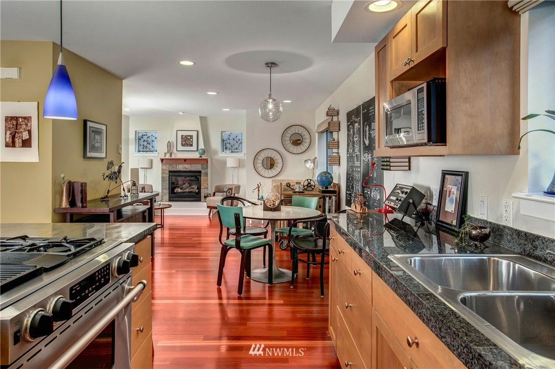 921 North 35th Street, Unit C Seattle, WA 98103 - Photo 3 of 17 a kitchen with stainless steel appliances granite countertop a stove top oven a sink a dining table and chairs with wooden floor