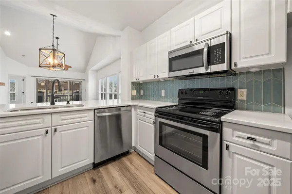 a kitchen with cabinets stainless steel appliances and wooden floor