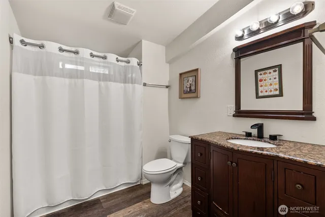 a bathroom with a granite countertop sink toilet and a mirror