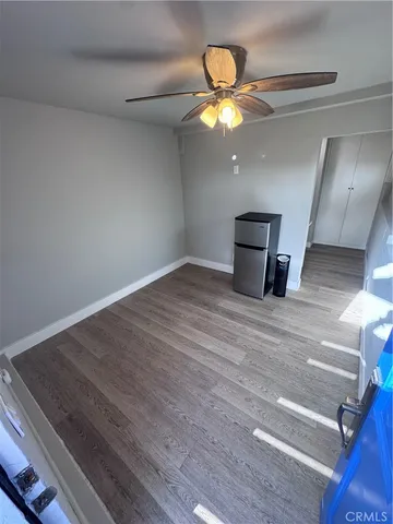 a view of an empty room with wooden floor and window