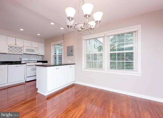 a kitchen with wooden floors and white cabinets