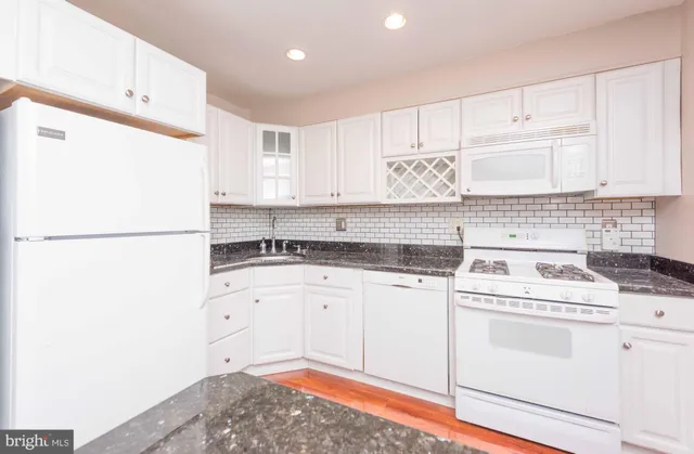 a kitchen with granite countertop white cabinets and white appliances