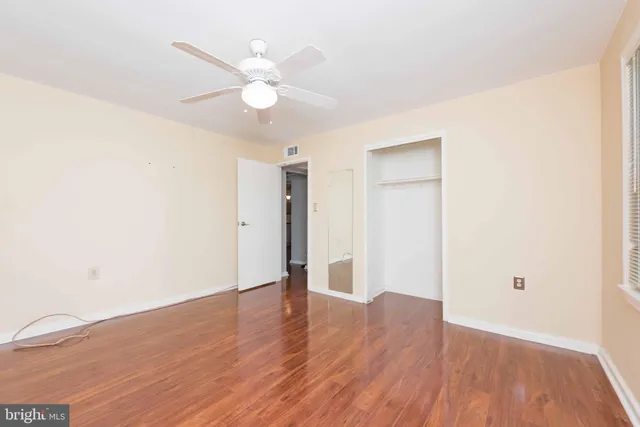 an empty room with wooden floor and fan