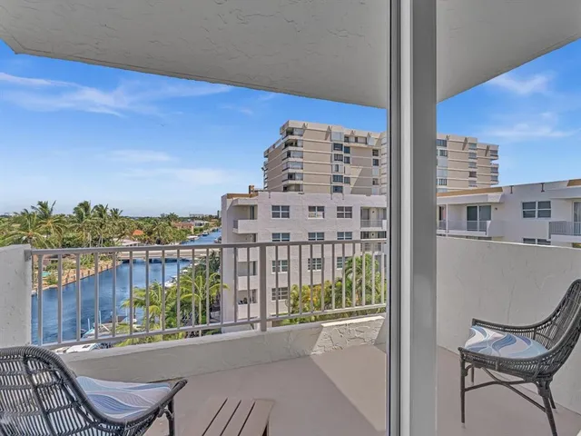 a view of a balcony with wooden chairs and city view
