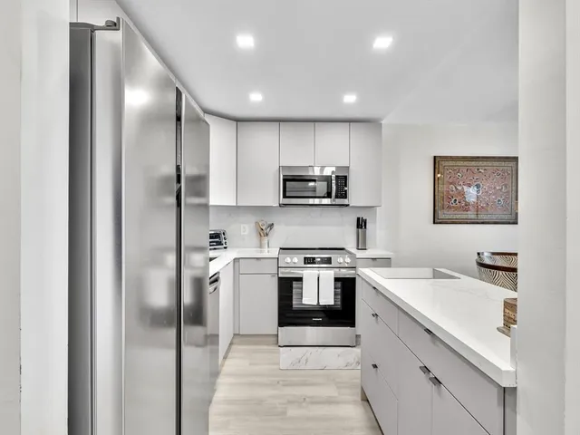 a kitchen with a sink stainless steel appliances and white cabinets