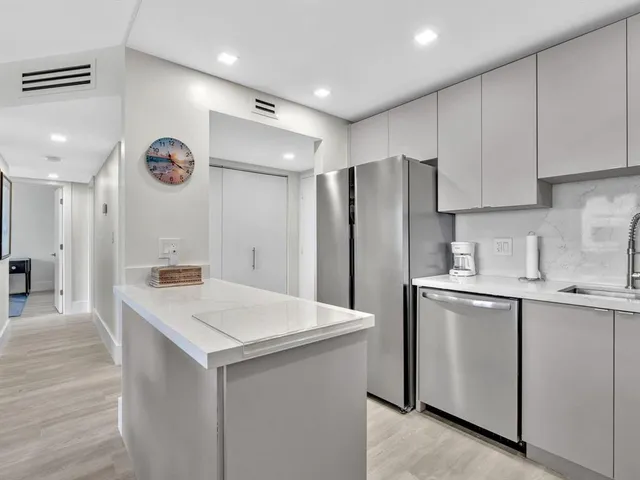 a kitchen with kitchen island a sink stainless steel appliances and white cabinets