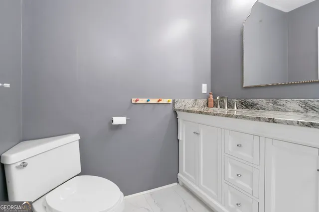 a bathroom with a granite countertop toilet sink and mirror