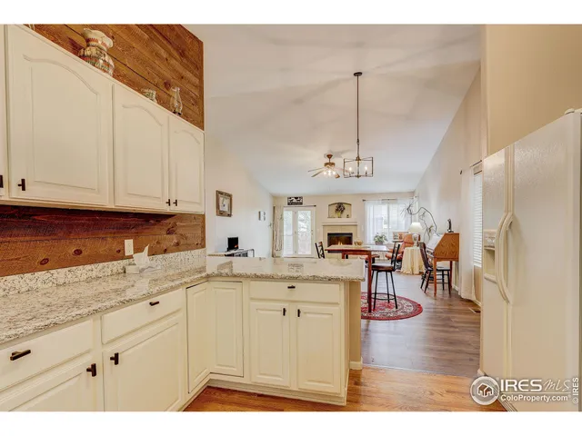 a open kitchen with granite countertop a stove a sink a dining table and chairs with wooden floor