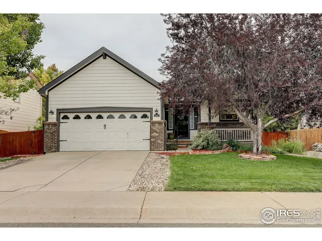 a view of a white house in front of a big yard with large trees