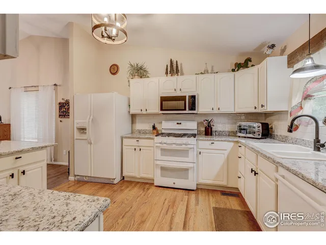 a kitchen with stainless steel appliances granite countertop a refrigerator sink and white cabinets