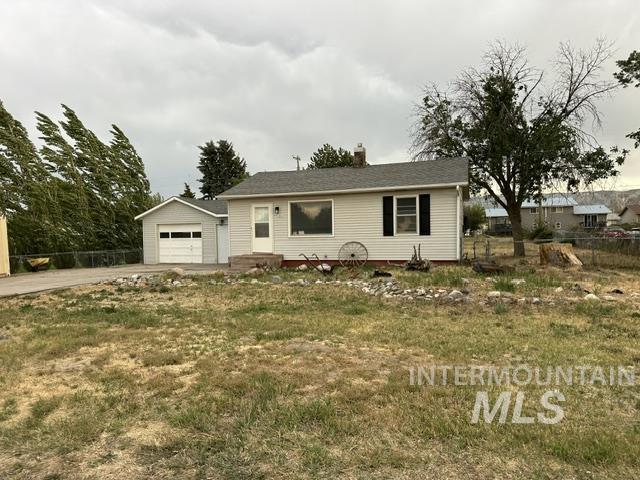 1301 Ridge Street Pocatello, ID 83201 - Photo 11 of 12 Single-story residence featuring light-colored siding, a dark roof, and a detached single-car garage with a panel door