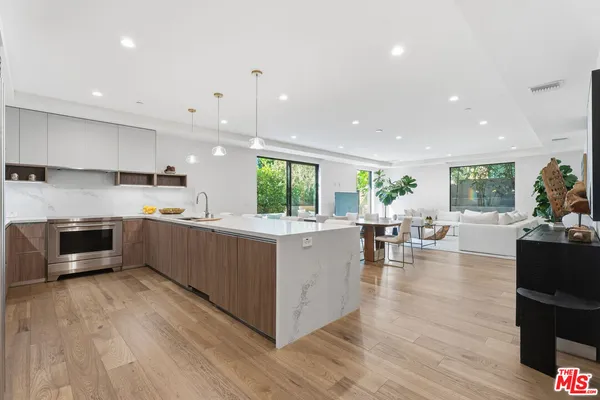 a kitchen with stainless steel appliances granite countertop wooden floors and view living room