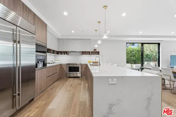 a large kitchen with stainless steel appliances a large counter top a refrigerator and a sink