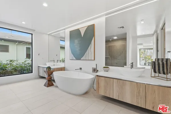 a spacious bathroom with a double vanity sink mirror and a bathtub