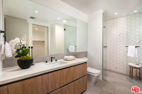 a bathroom with a granite countertop sink a toilet a mirror and shower