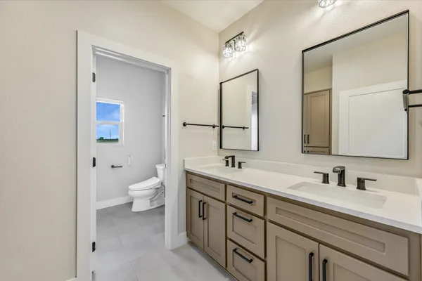 a spacious bathroom with a double vanity sink toilet mirror and shower