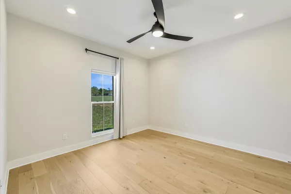 a view of an empty room with window and chandelier fan