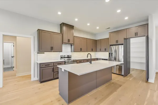 a large kitchen with stainless steel appliances granite countertop a sink and cabinets with wooden floor