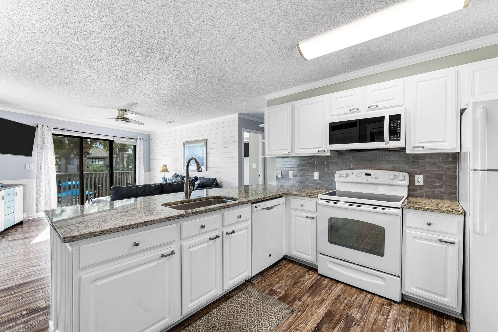 285 Payne Street, Unit 19B Destin, FL 32550 - Photo 10 of 29 a kitchen with granite countertop a sink stainless steel appliances and white cabinets