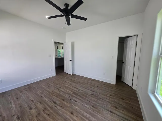 an empty room with wooden floor and a ceiling fan