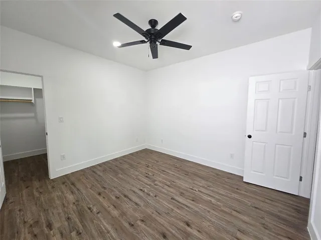 an empty room with wooden floor and ceiling fan
