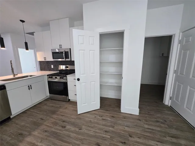 a kitchen with white cabinets and appliances