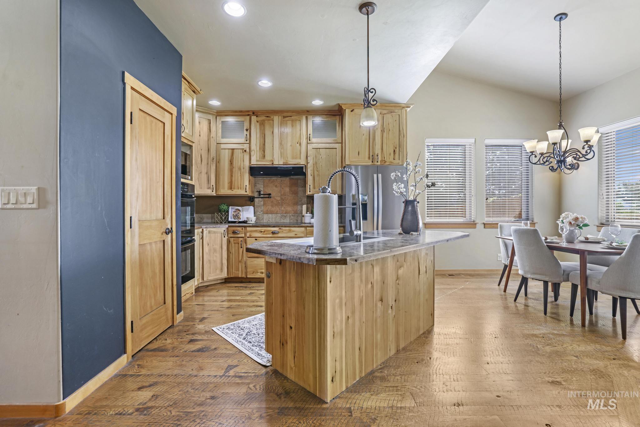 205 Edwards Drive Twin Falls, ID 83301 - Photo 12 of 49 Kitchen featuring light brown cabinets, decorative light fixtures, decorative backsplash, light wood-style flooring, and vaulted ceiling