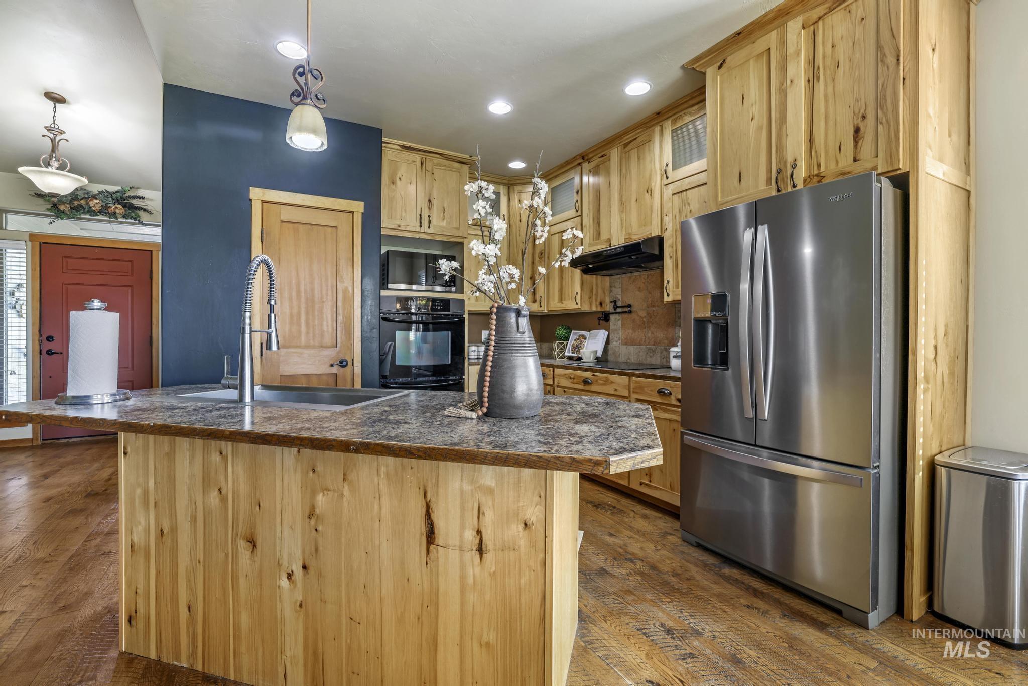 205 Edwards Drive Twin Falls, ID 83301 - Photo 14 of 49 Kitchen featuring dark countertops, black appliances, hanging light fixtures, dark wood-style floors, and light brown cabinets