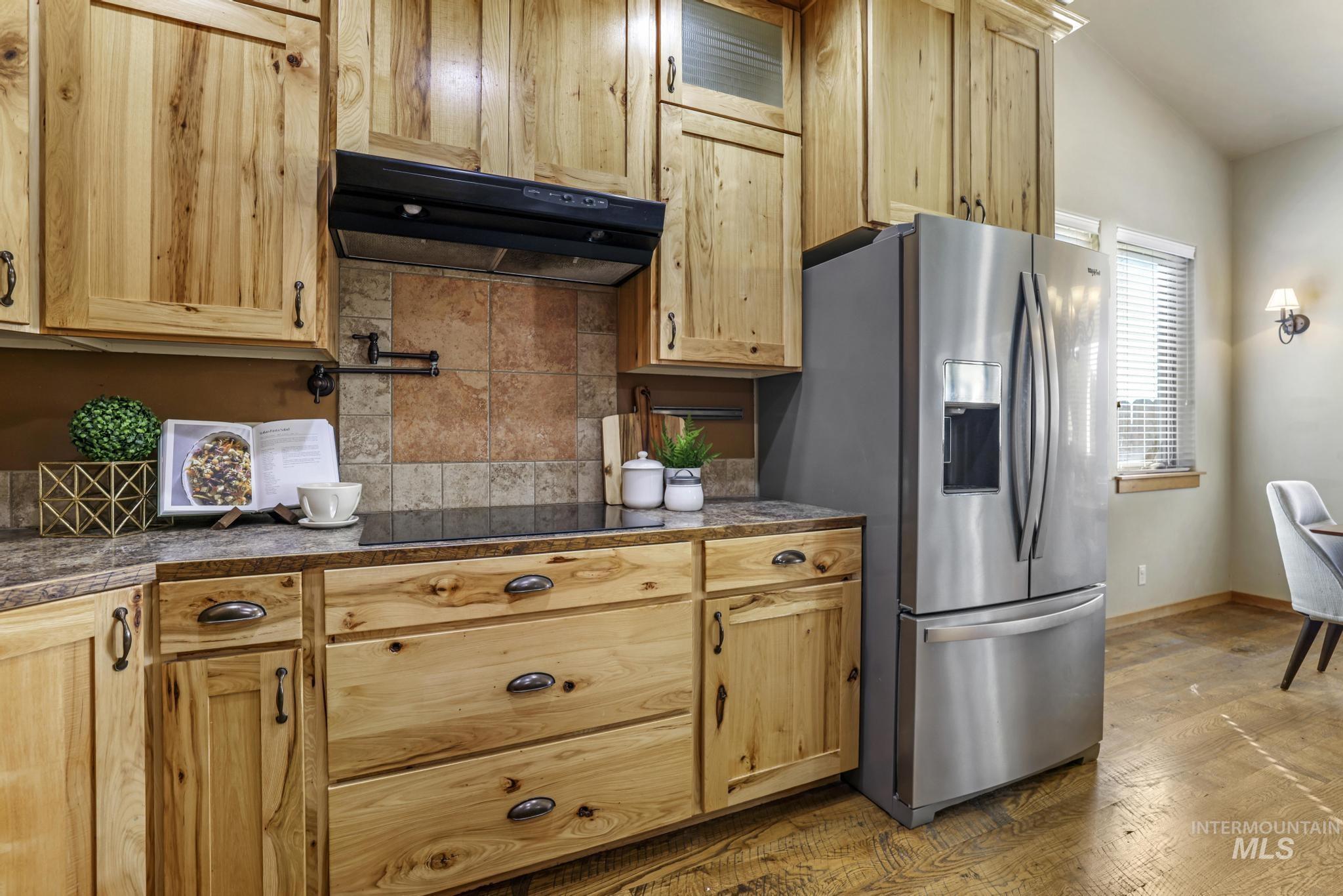 205 Edwards Drive Twin Falls, ID 83301 - Photo 15 of 49 Kitchen with under cabinet range hood, decorative backsplash, dark wood-type flooring, stainless steel refrigerator with ice dispenser, and tile counters