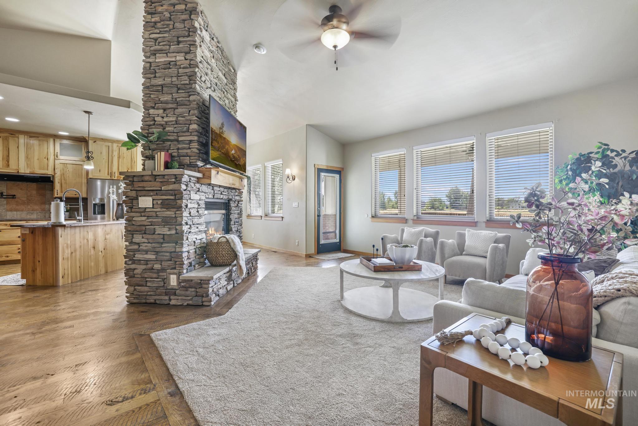 205 Edwards Drive Twin Falls, ID 83301 - Photo 5 of 49 Living room featuring a ceiling fan, dark wood-style flooring, a stone fireplace, and vaulted ceiling
