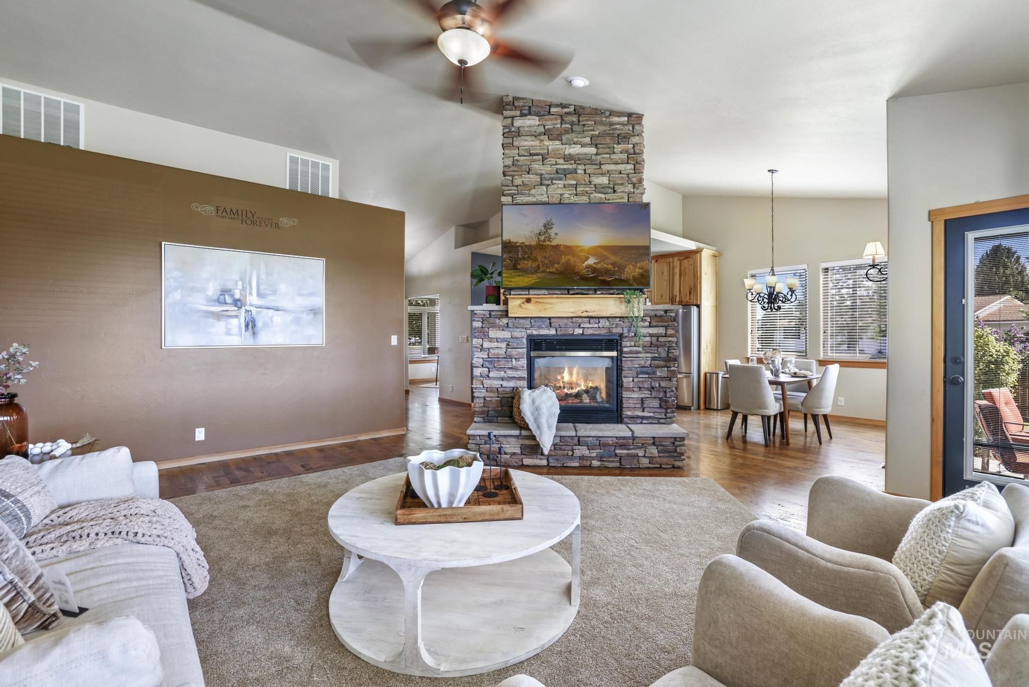 205 Edwards Drive Twin Falls, ID 83301 - Photo 6 of 49 Living room with wood finished floors, a fireplace, lofted ceiling, ceiling fan, and a chandelier