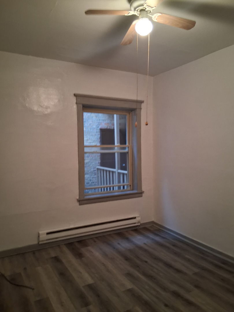 3920 North Broadway, Unit 202 Chicago, IL 60613 - Photo 2 of 7 a view of an empty room with wooden floor and a window