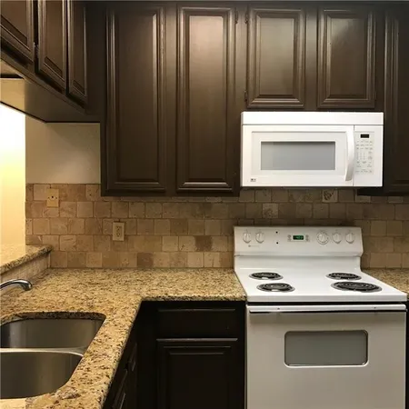 a kitchen with granite countertop a stove sink and cabinets