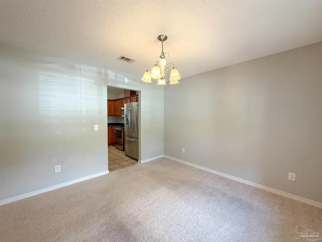an empty room with chandelier and hallway