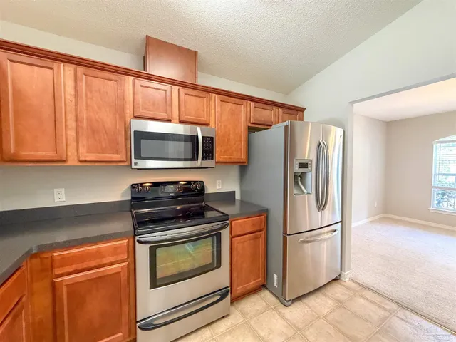a kitchen with granite countertop a refrigerator stove and microwave