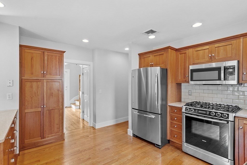 21 Cottage Street Hamilton, MA 01982 - Photo 5 of 40 a kitchen with stainless steel appliances a refrigerator a stove top oven and wooden floor