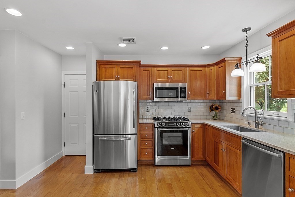 21 Cottage Street Hamilton, MA 01982 - Photo 7 of 40 a kitchen with stainless steel appliances granite countertop a refrigerator a sink a stove a microwave and island with wooden floor