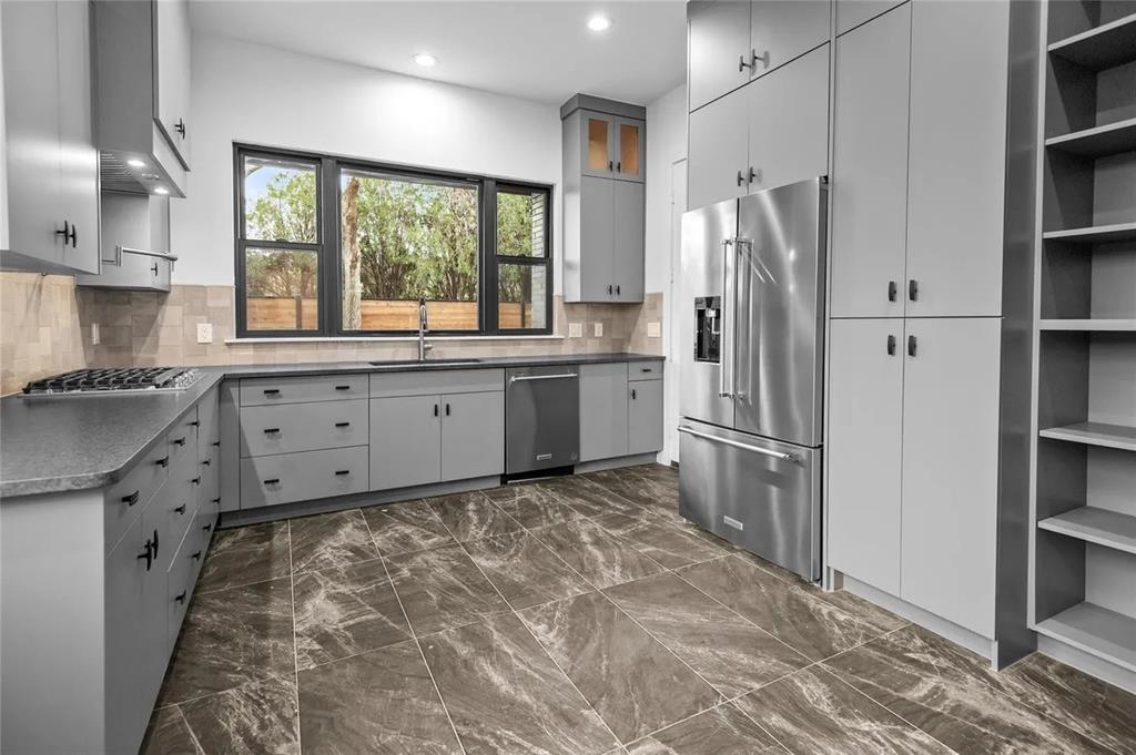 309 Kaye Street Coppell, TX 75019 - Photo 28 of 36 Modern kitchen featuring grey cabinetry, dark marble-finish flooring, and a large multi-pane window