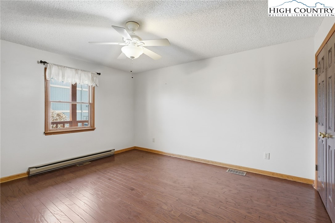 155 Glen Burney Road, Unit C4 Blowing Rock, NC 28605 - Photo 12 of 15 an empty room with wooden floor chandelier fan and windows